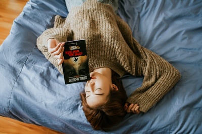 女人的毛衣拿着书躺在床上
